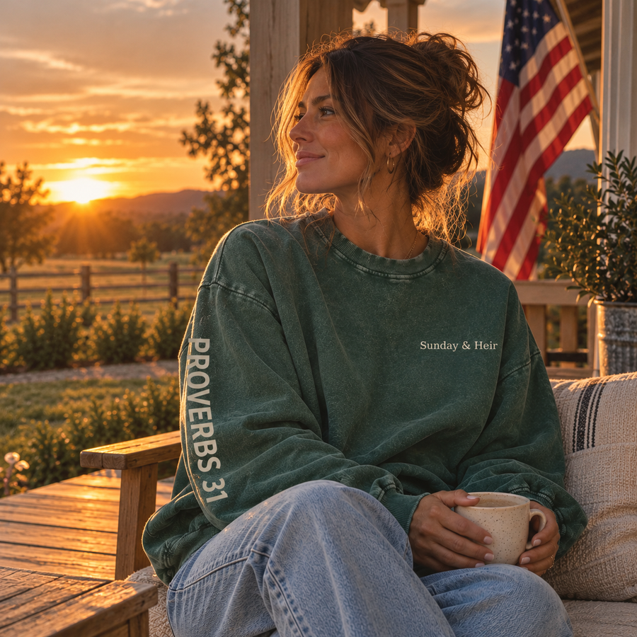 Woman wearing Sunday & Heir forest green Proverbs 31 oversized sweatshirt on farmhouse porch at sunset